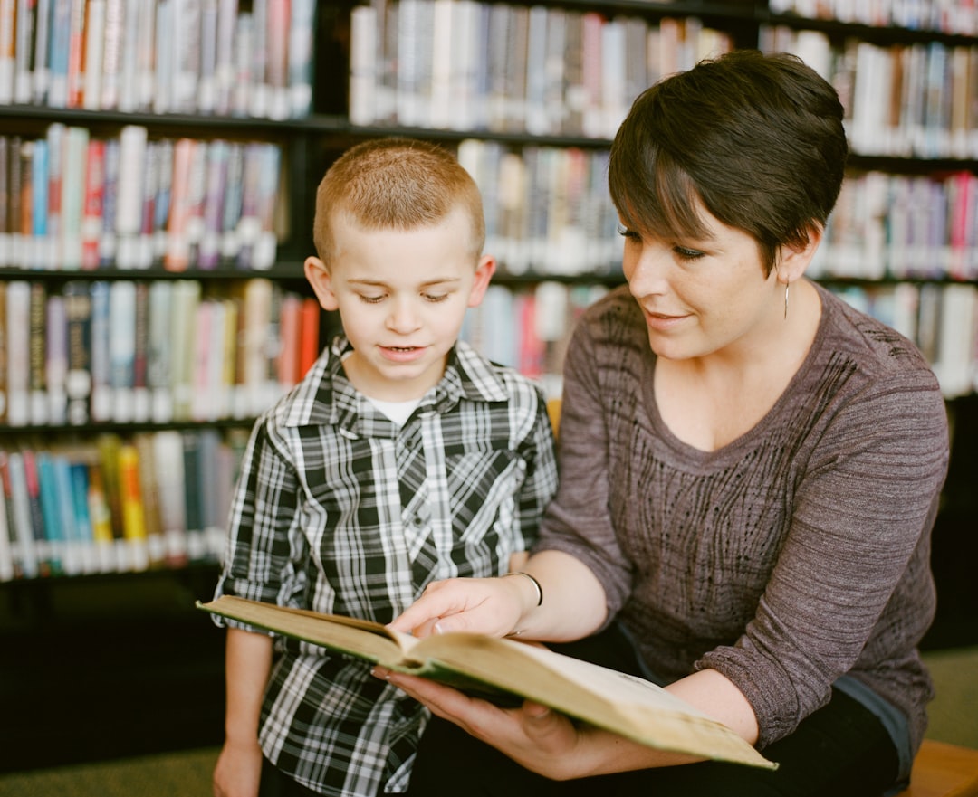 gallery-04 Mother reading to her son as he listens intently. Books in the background are slightly blurred creating the perfect atmosphere to instill a lifelong love of reading. The 3 - 6 year old boy is engaged, happy, the moment is captured in this photo creating a lifelong memory. nnhttps://www.awcreativeut.comnhttps://www.instagram.com/AwCreativeUT/nhttps://www.citystorageif.com/nhttps://www.etsy.com/shop/AwCreativeUTnn#AwCreativeUT #awcreative #AdamWinger