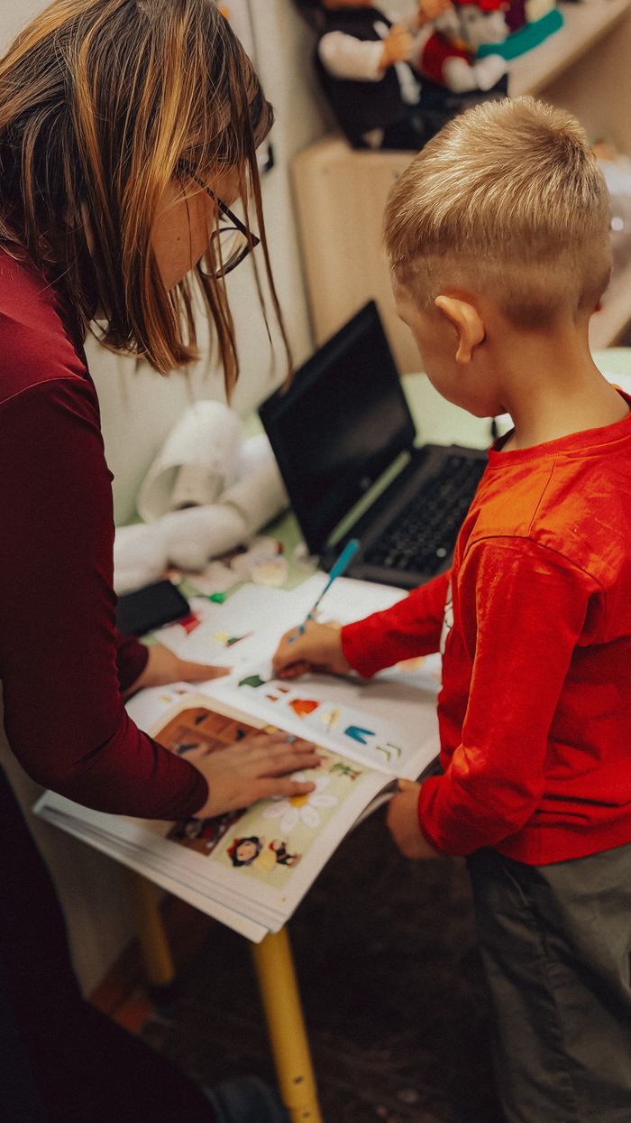 Offerings Teacher assisting a child with educational activities in a learning environment.